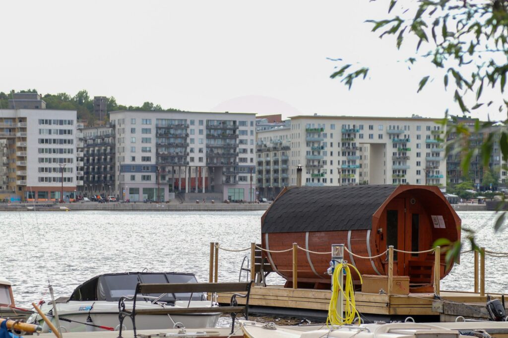 Fasssauna auf einem Steg am Hafen vor Wohnblöcken