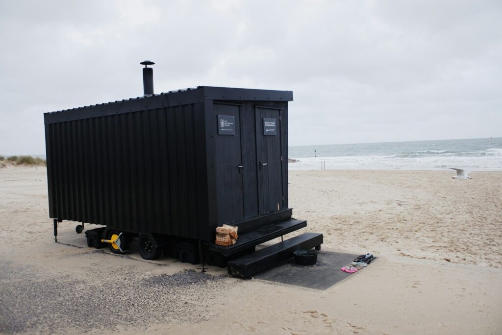Schwarze mobile Sauna auf einem Anhänger am Sandstrand