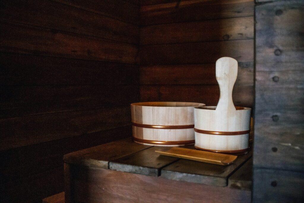 Zwei Holzkübel mit Messingbändern und eine Kelle in einer Sauna